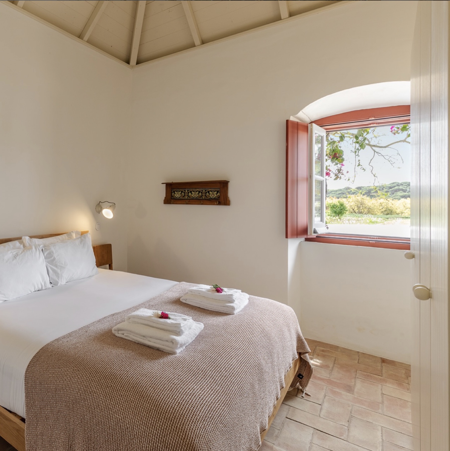A bright bedroom with timber furniture and an open garden view