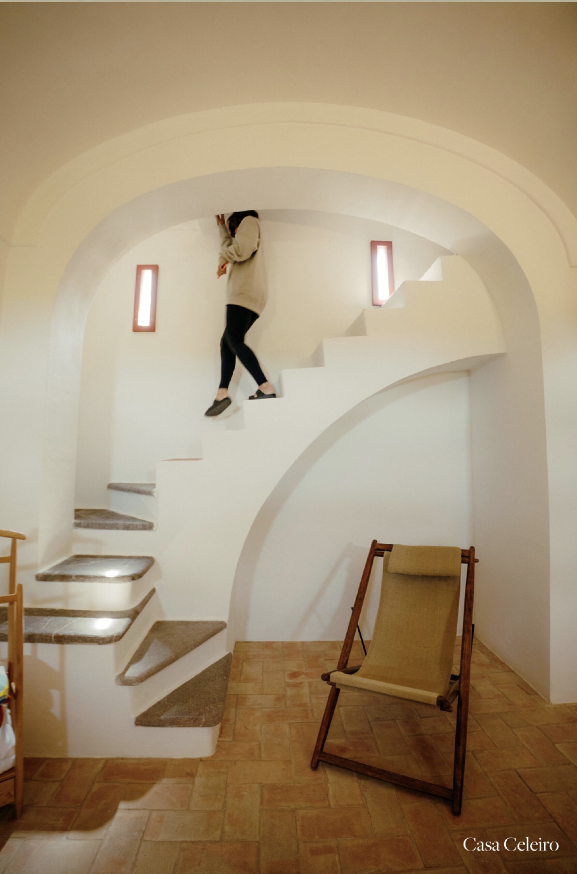 Curved white staircase and terracotta floor inside a guest house