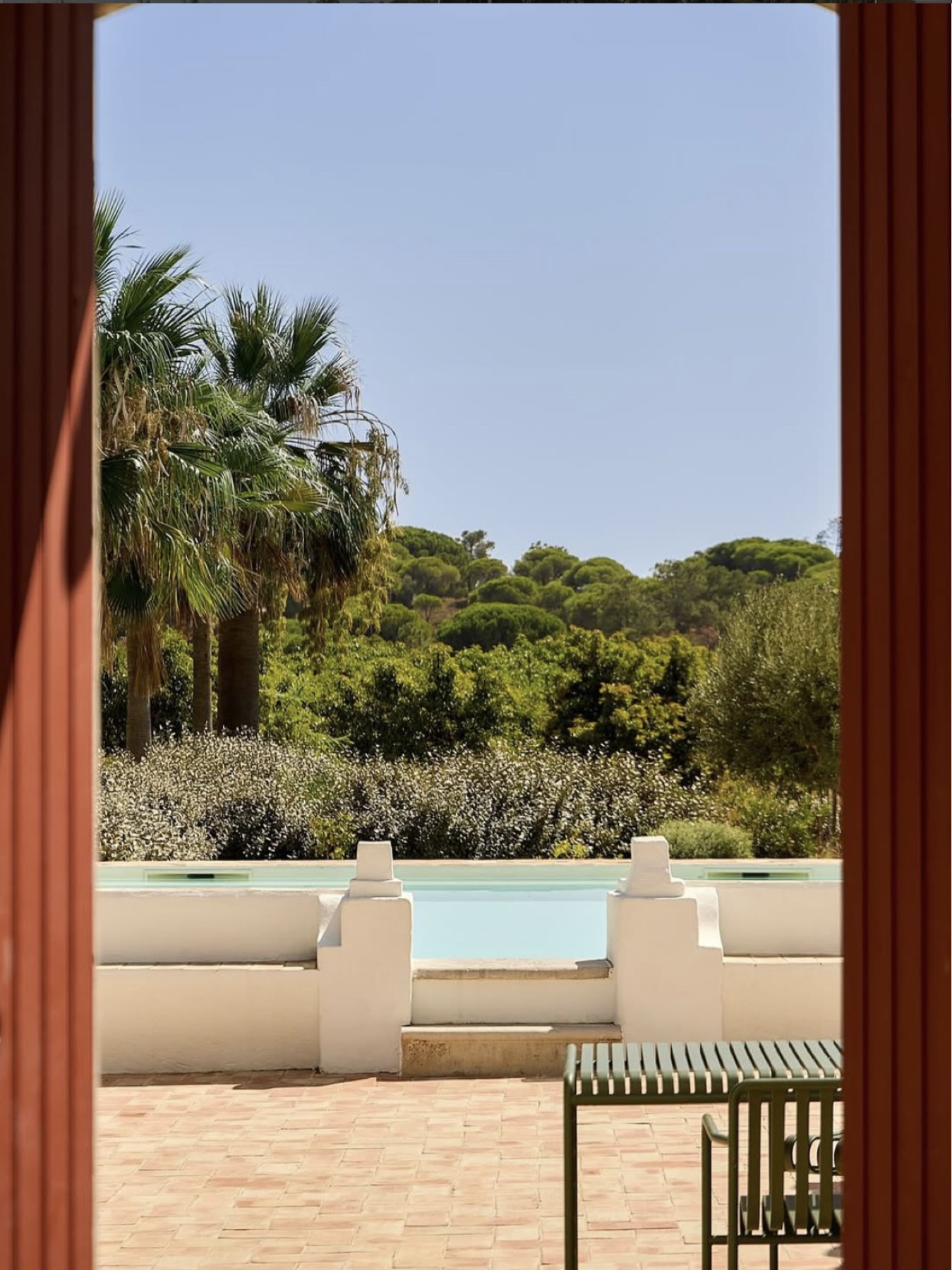 The pool and palms framed by an open red doorway